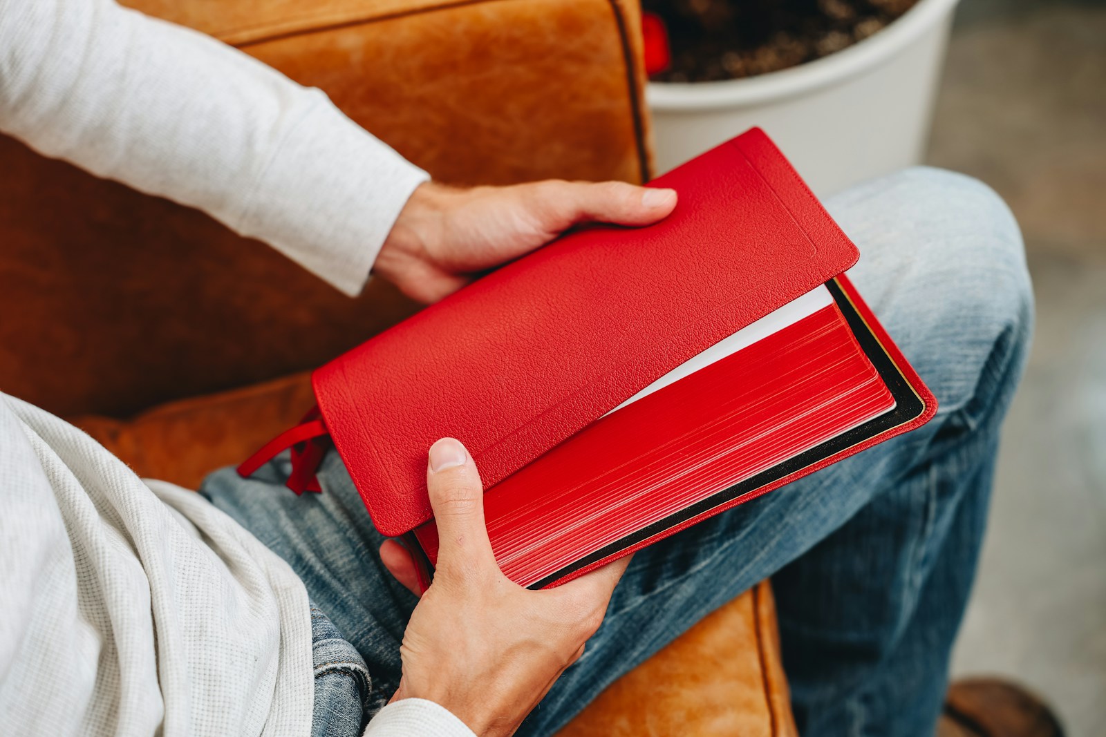 A person sitting on a couch holding a red folder